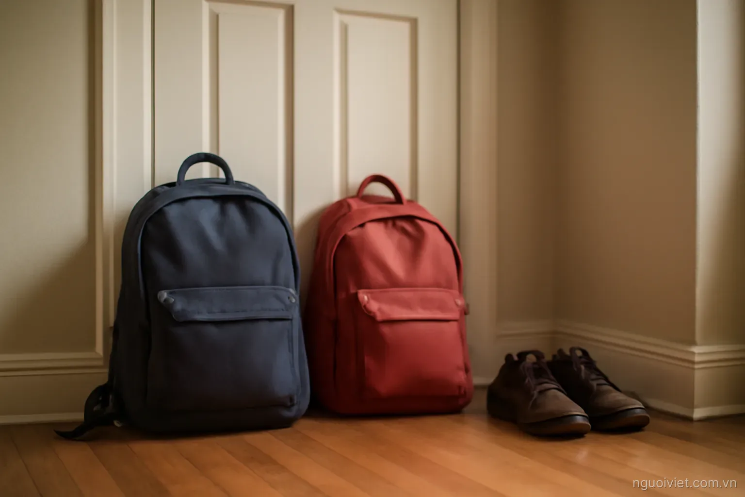 two school bags left by a doorway beside a pair of adult shoes in a hallway